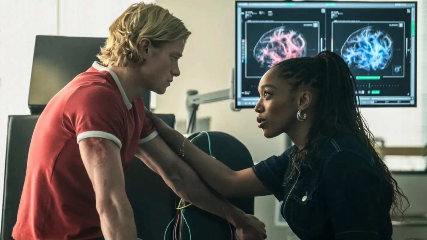 Tom Rhys Harries e Naomi Ackie em cena de laboratório, com exames de cérebro em monitores