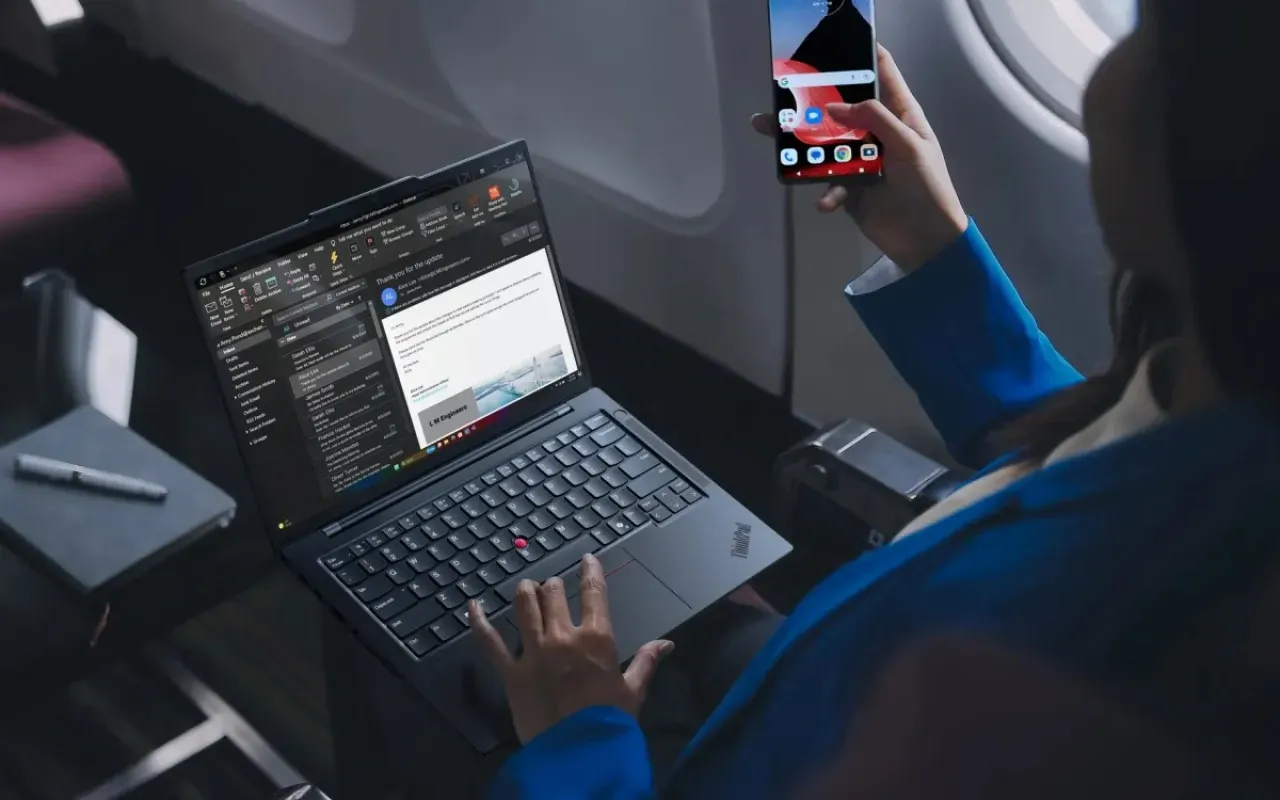 Profissional usa um notebook Lenovo numa mesa de trabalho, com outro funcionário ao fundo