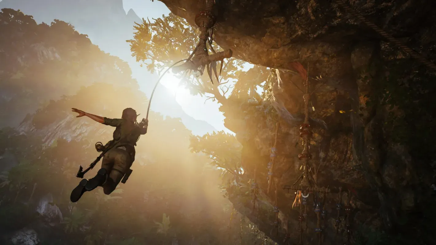Lara Croft se balança em uma corda diante de um penhasco iluminado pelo sol em Shadow of the Tomb Raider