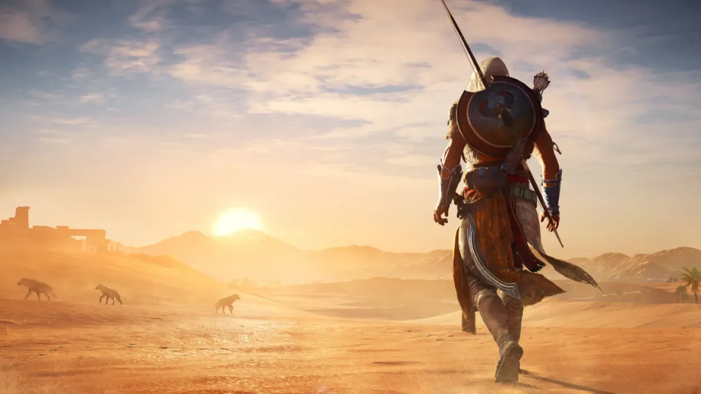 Bayek caminha pelo deserto ao pôr do sol em Assassin's Creed Origins