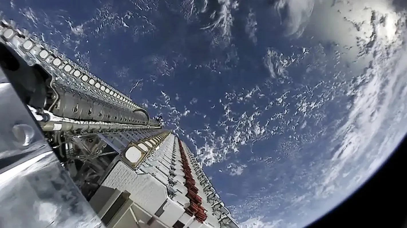 Lote de satélites Starlink empilhados no foguete, com a Terra ao fundo