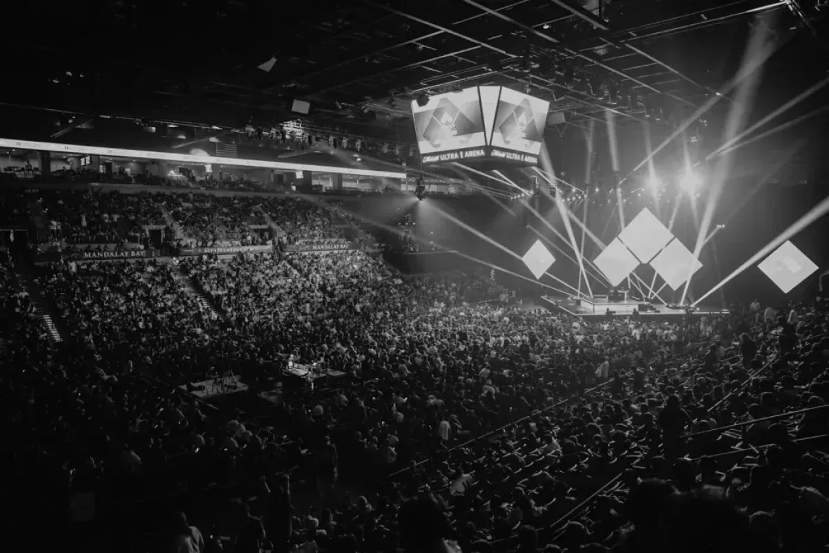 Público lota a arena da Evo durante uma final, com o palco iluminado ao fundo